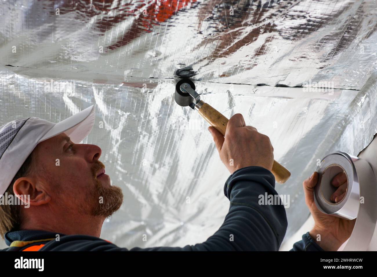 the construction worker uses aluminum tape and they had a roller for ...