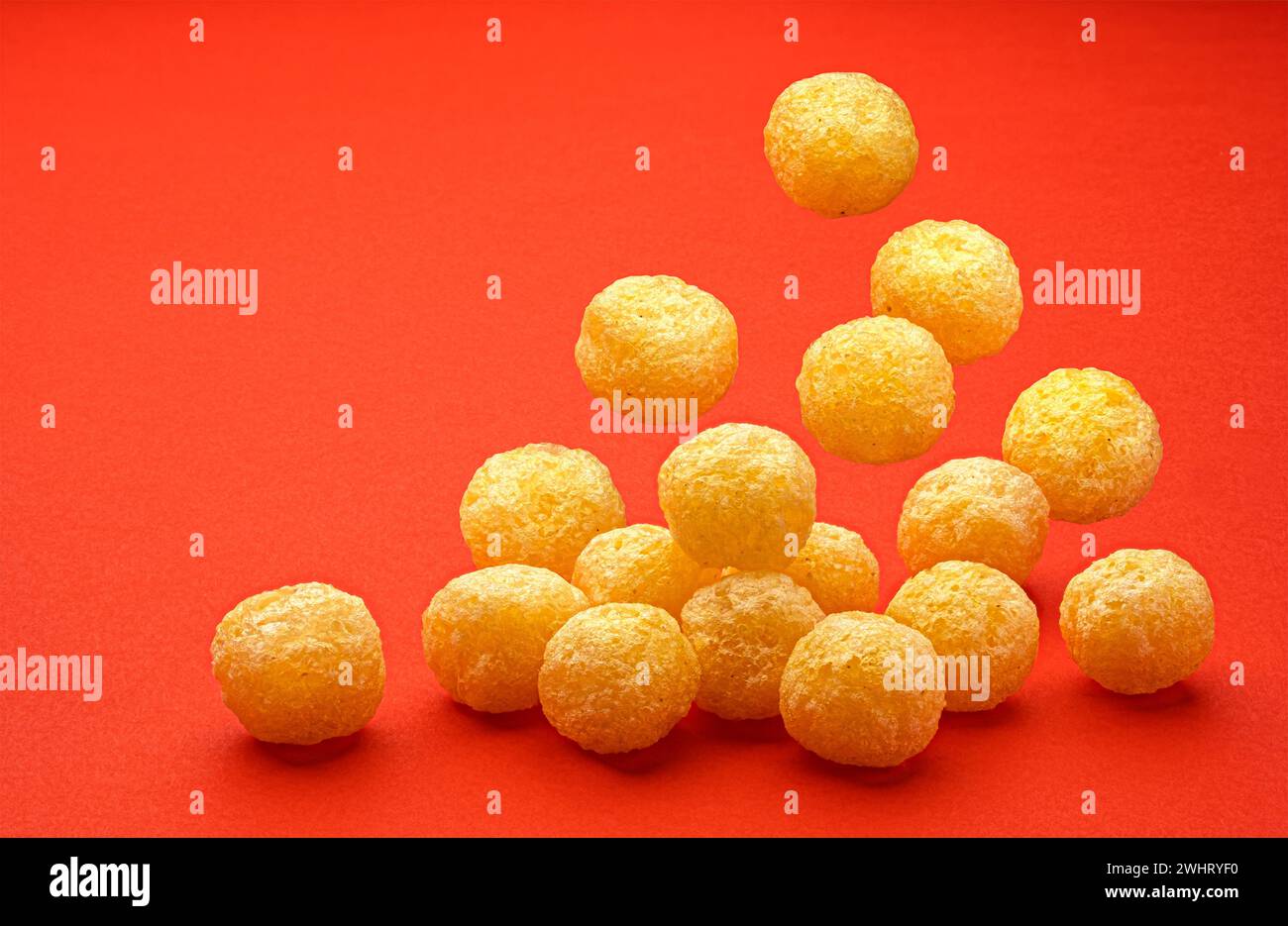 Falling corn balls isolated on red background, full depth of field Stock Photo