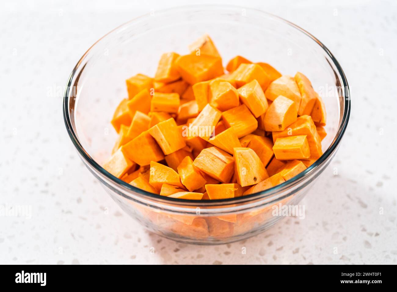 Seasoning cubed sweet potatoes to make ovenroasted sweet potatoes