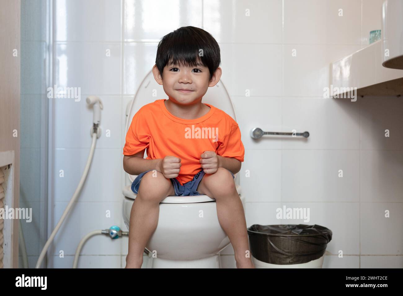 Asian boy Sitting on the toilet bowl Stock Photo