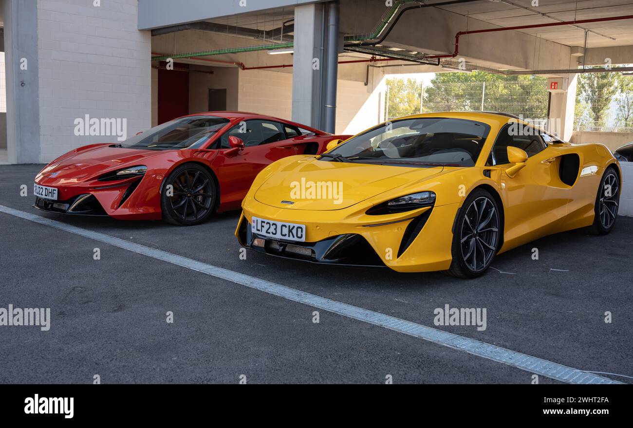 Front view of a pair of modern McLaren Artura supercars, one red and the other yellow Stock Photo