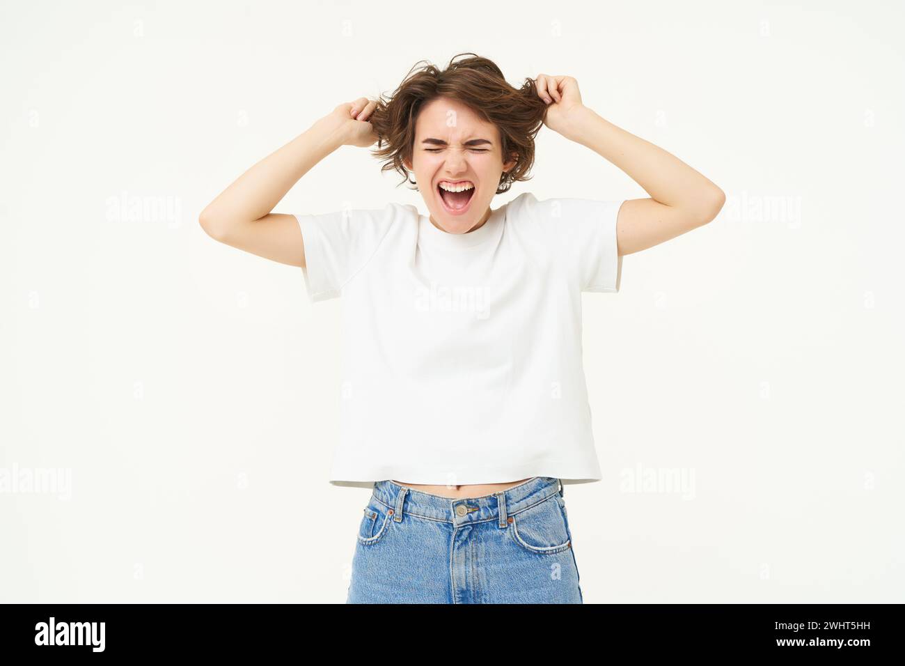 Portrait of angry, outraged woman pulls her hair out, screaming, losing