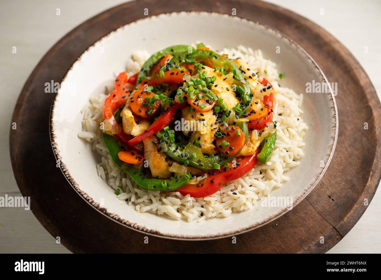 Chicken cooked in a wok with colorful peppers and rice. Stock Photo