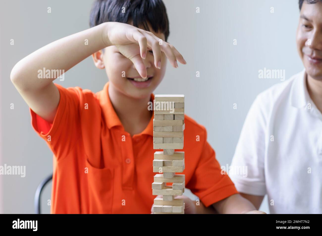 Asian father and son playing wood blocks game Carefree kid playing wood blocks game building constructor from blocks with father Stock Photo