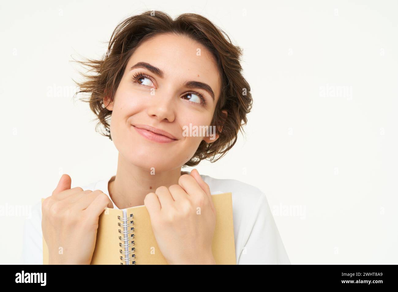 Portrait of happy, beautiful woman holding planner, making notes, doing her homework, standing over white background Stock Photo