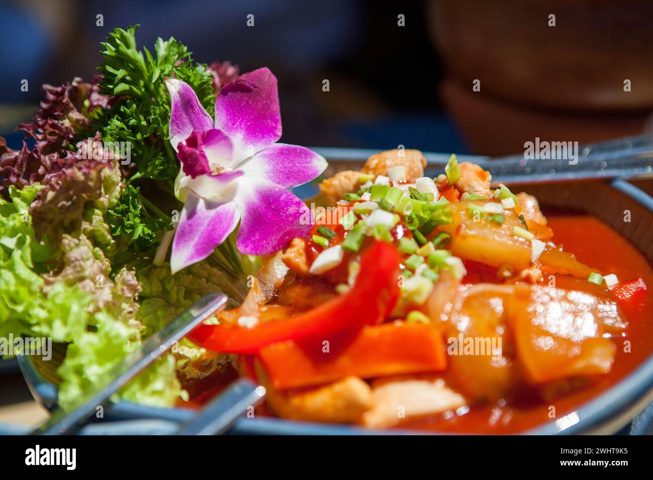 Exquisite Thai Culinary Art: Vibrant Thai Dish with Pink Flower Garnish Stock Photo