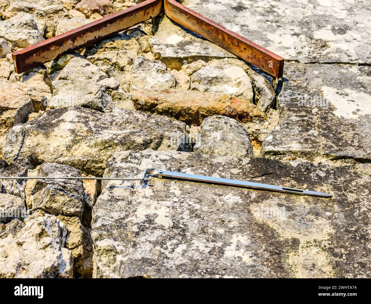 Tell-tale pivoted bar of metal to show potential movement in old stone wall - central France. Stock Photo