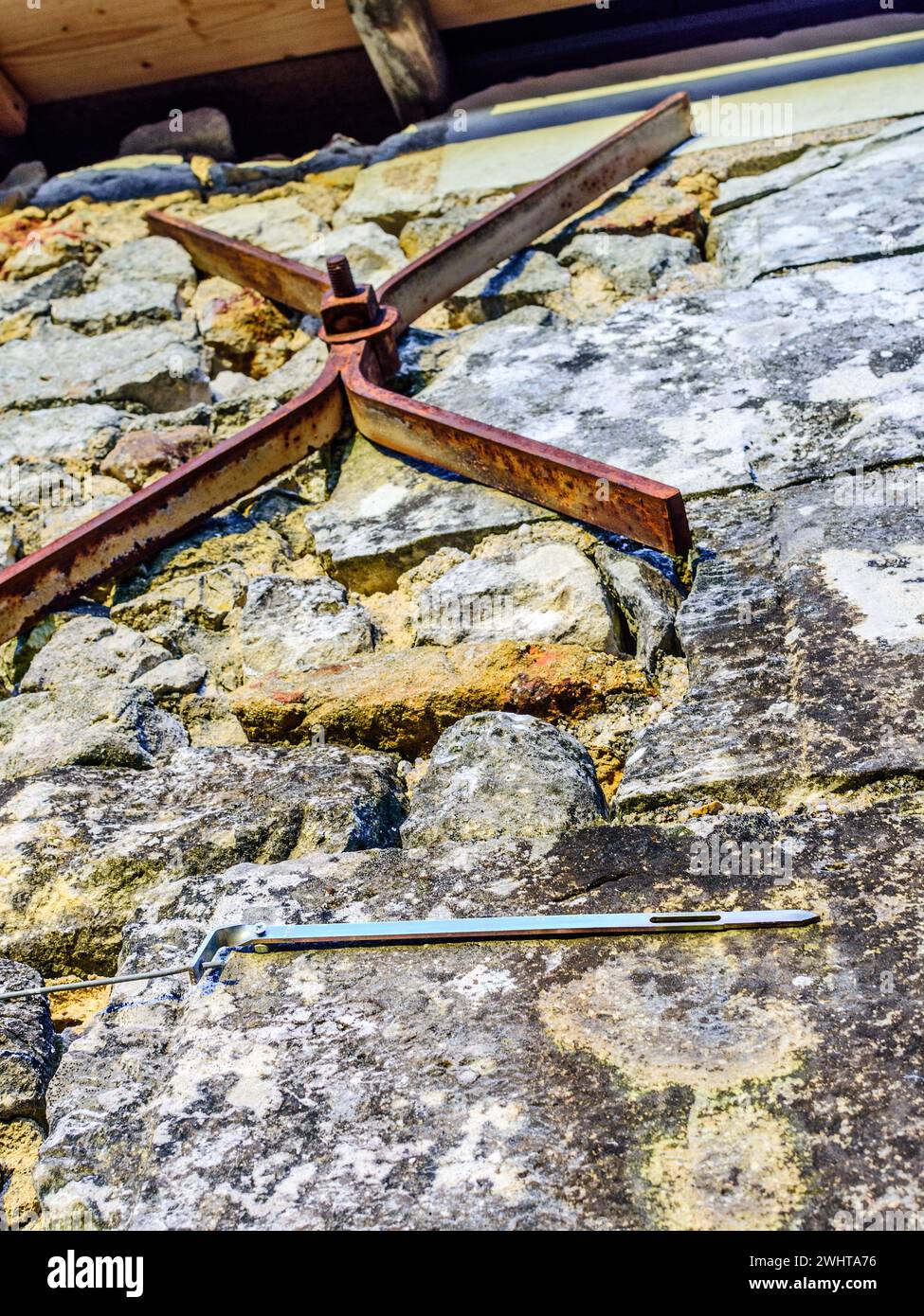 Tell-tale pivoted bar of metal to show potential movement in old stone wall - central France. Stock Photo