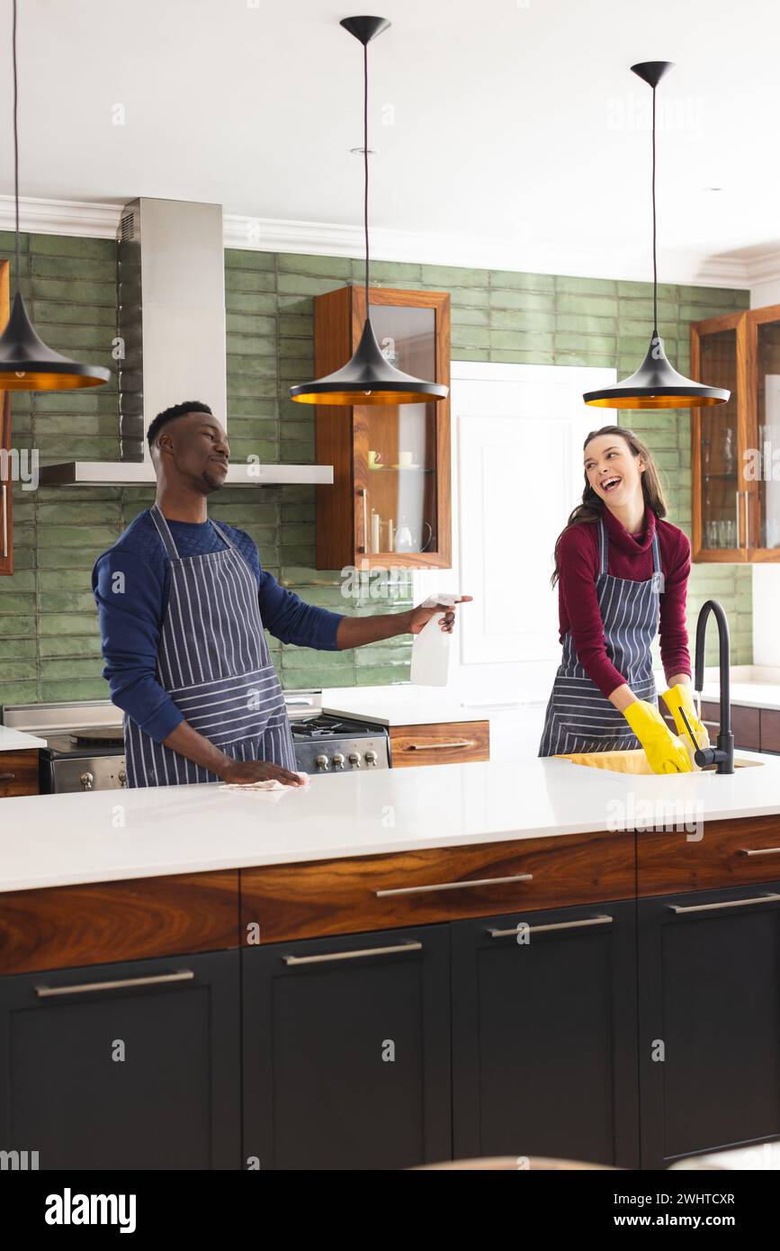 Happy diverse couple cleaning countertop and doing dishes in kitchen at home Stock Photo