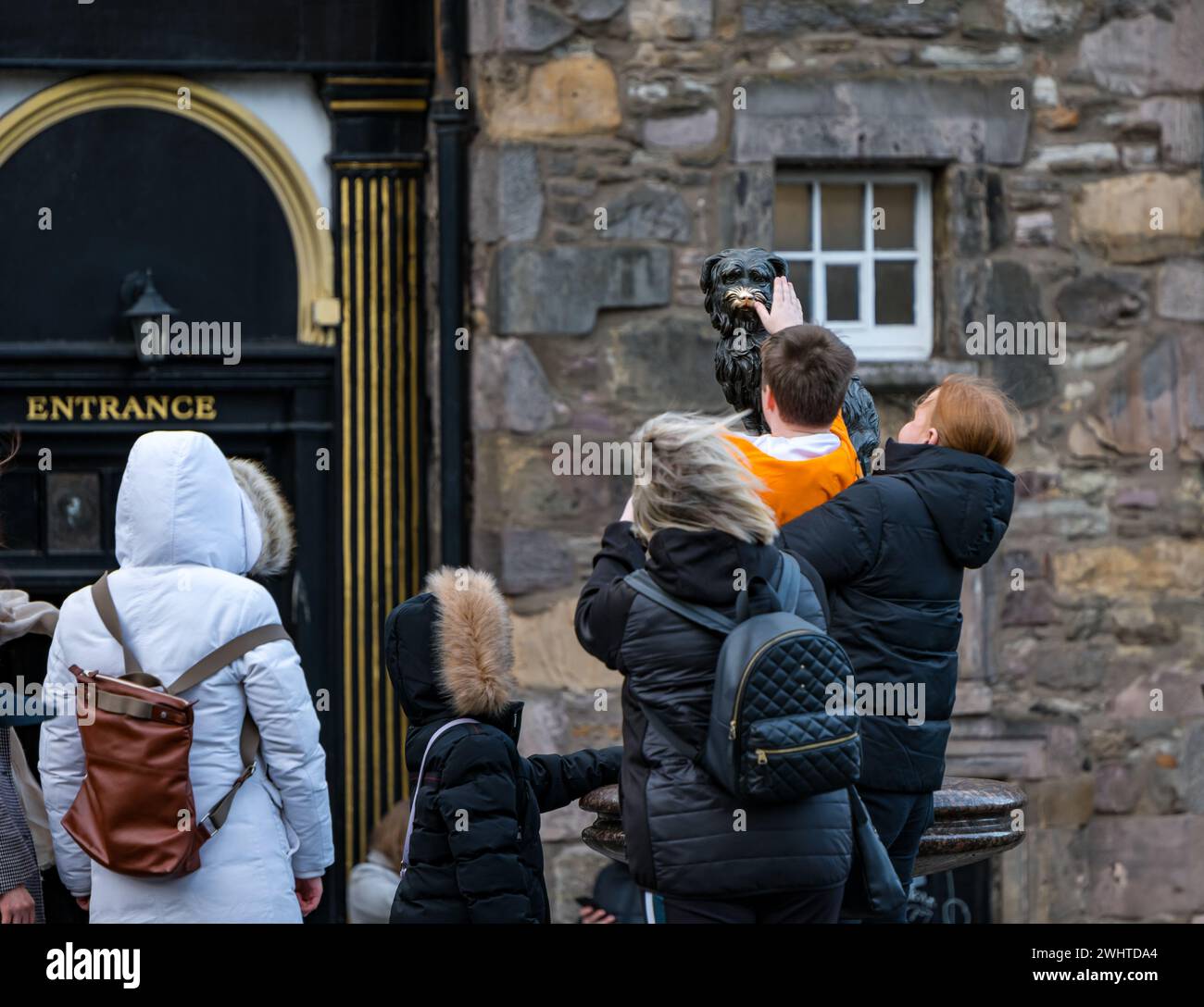 Tourist touching nose of Greyfriar's Bobby dog statue for good luck, Edinburgh, Scotland, UK Stock Photo