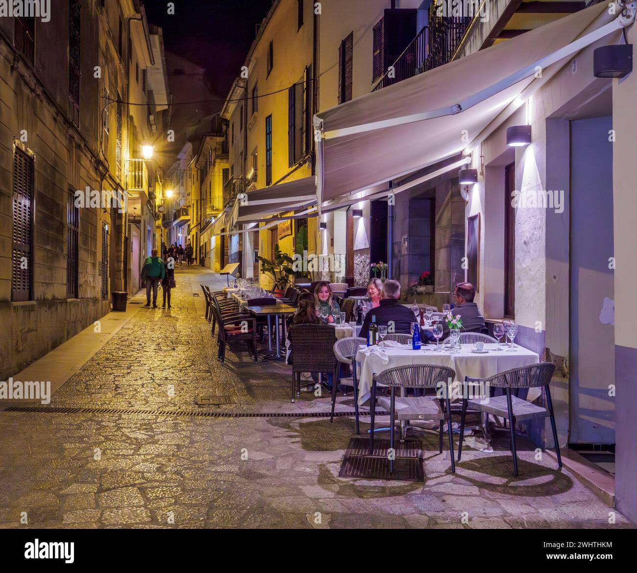 Night street scene with al fresco diners outside a restaurant in the town of Soller in the Tramuntana Mountains of Majorca Spain Stock Photo