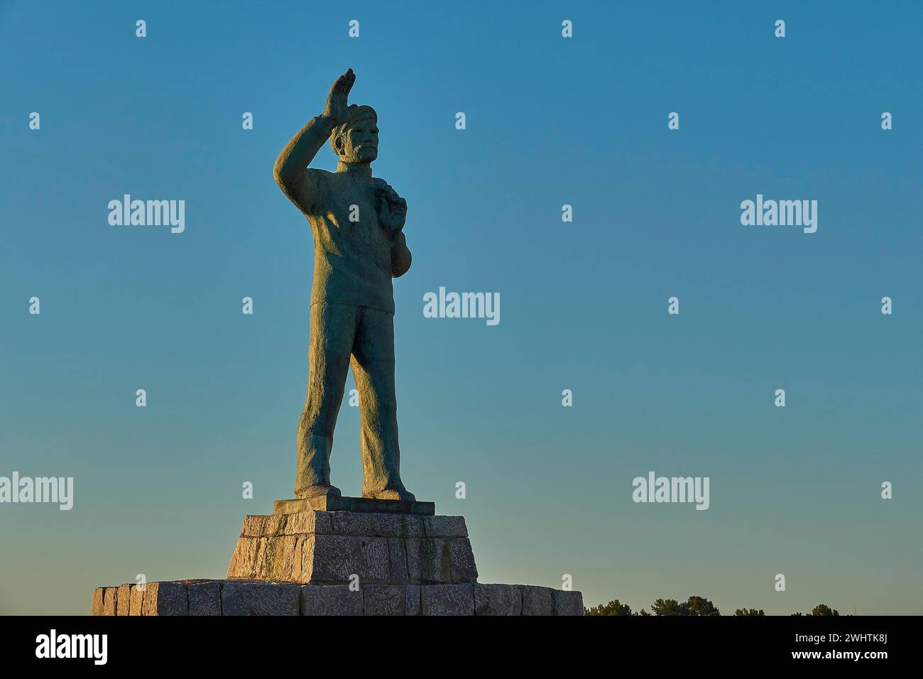 Statue of a man with his arm outstretched towards the sky at dawn, bronze statue of a waving sailor in memory of the souls lost at sea, Gythio, Mani Stock Photo