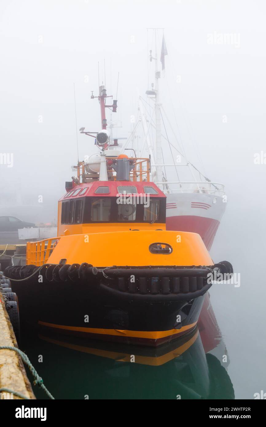 Fishing vessels in a foggy misty morning at Harbor Stock Photo