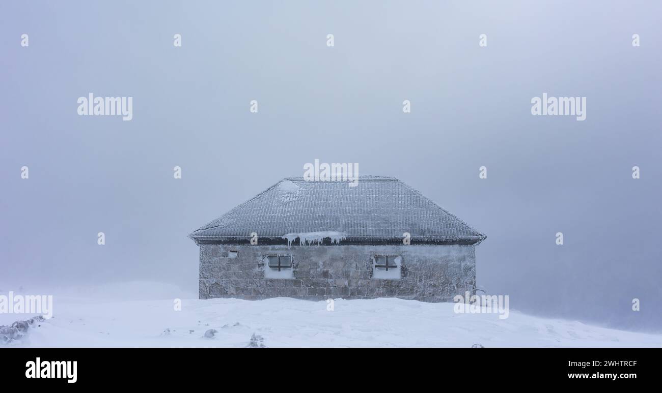 Dom Slaski mountain shelter belod Mount Sniezka. Hard weather conditions in the mountains. Buildings covered in ice. Photo taken on a cloudy winter da Stock Photo