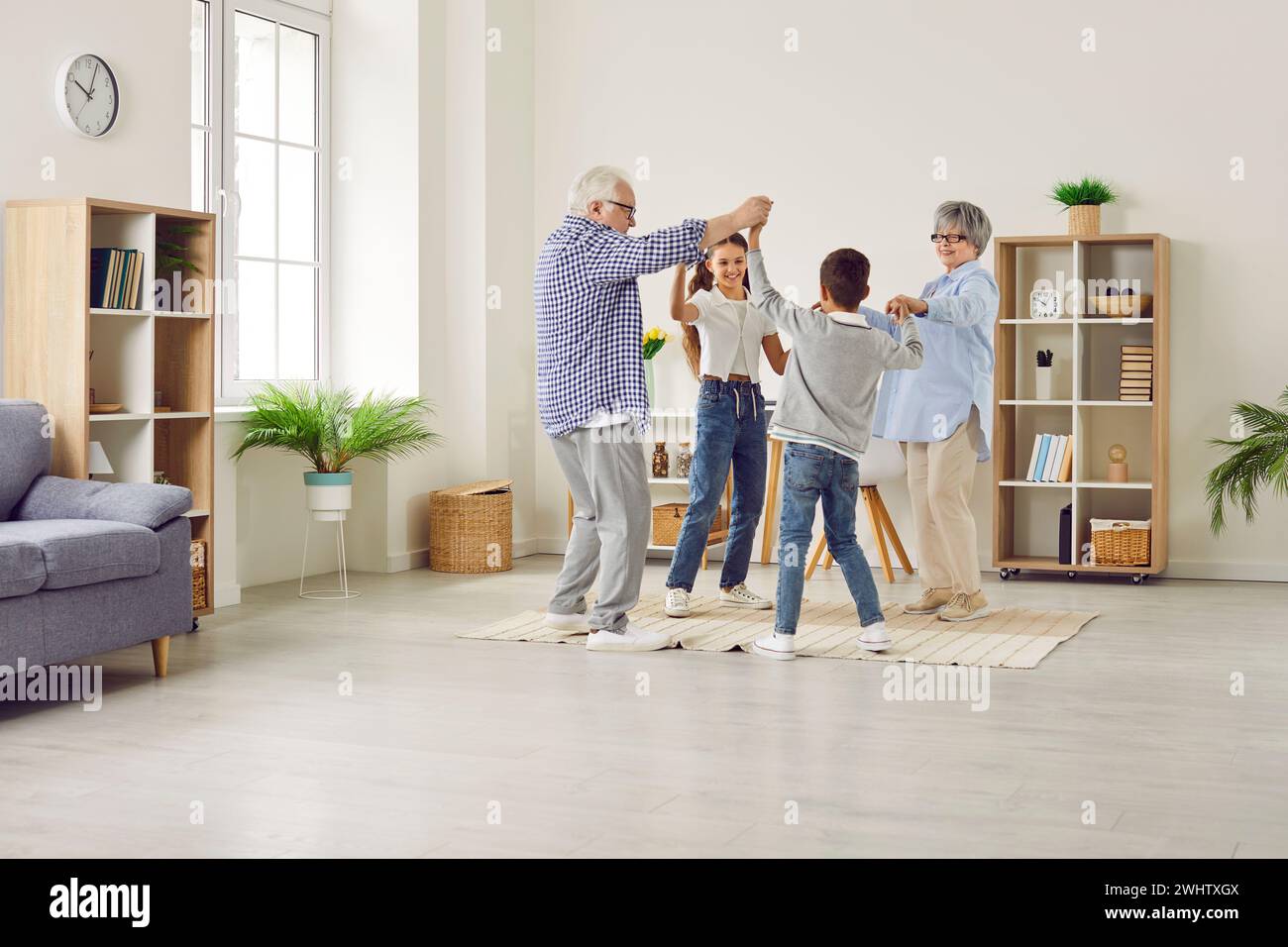 Happy children and grandparents dancing and having fun in the living room at home Stock Photo