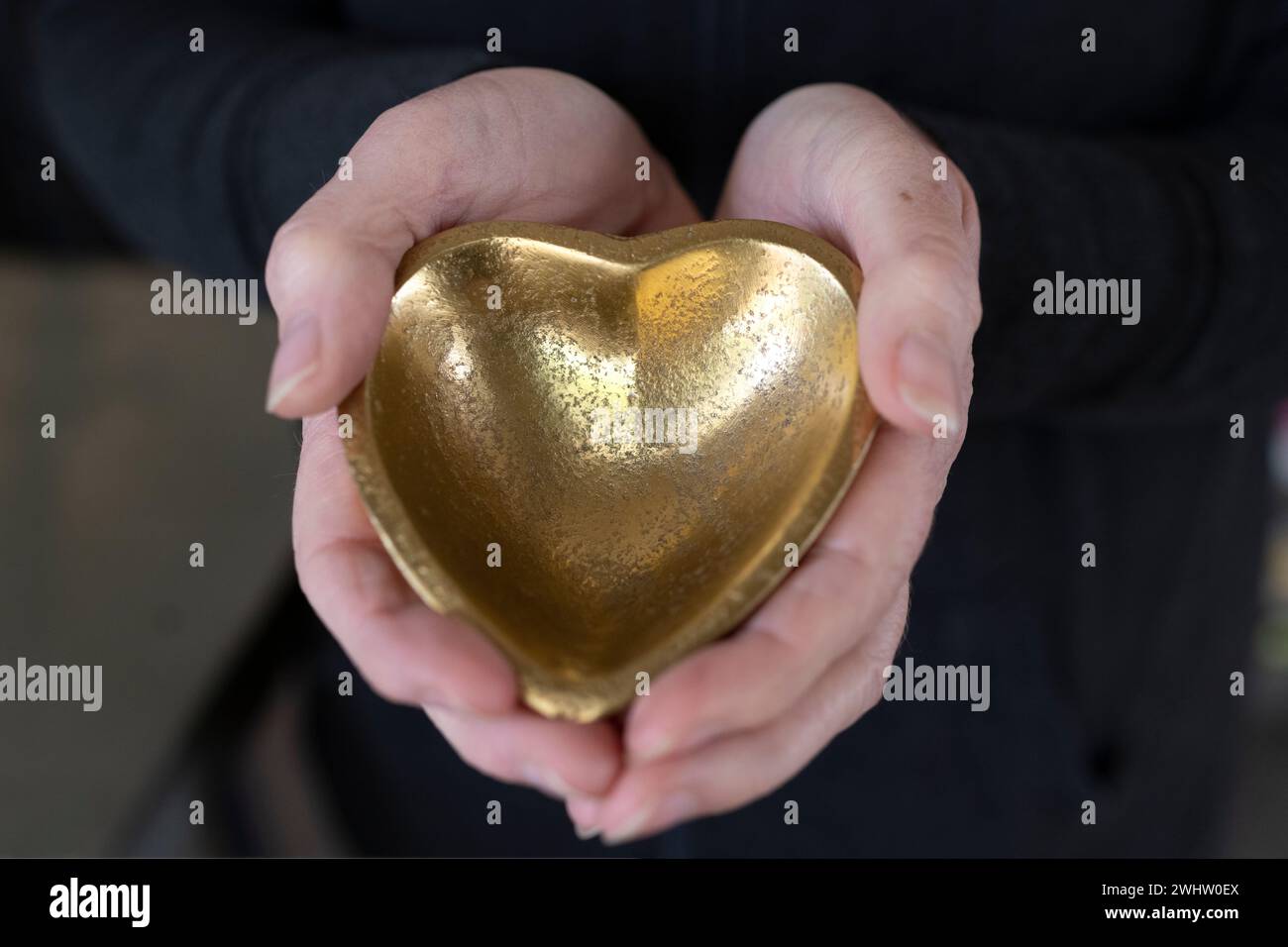 A person holds a heart-shaped metal object Stock Photo