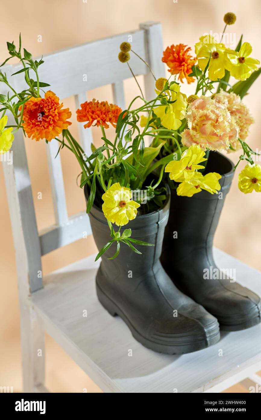 flowers in rubber boots on vintage chair Stock Photo - Alamy