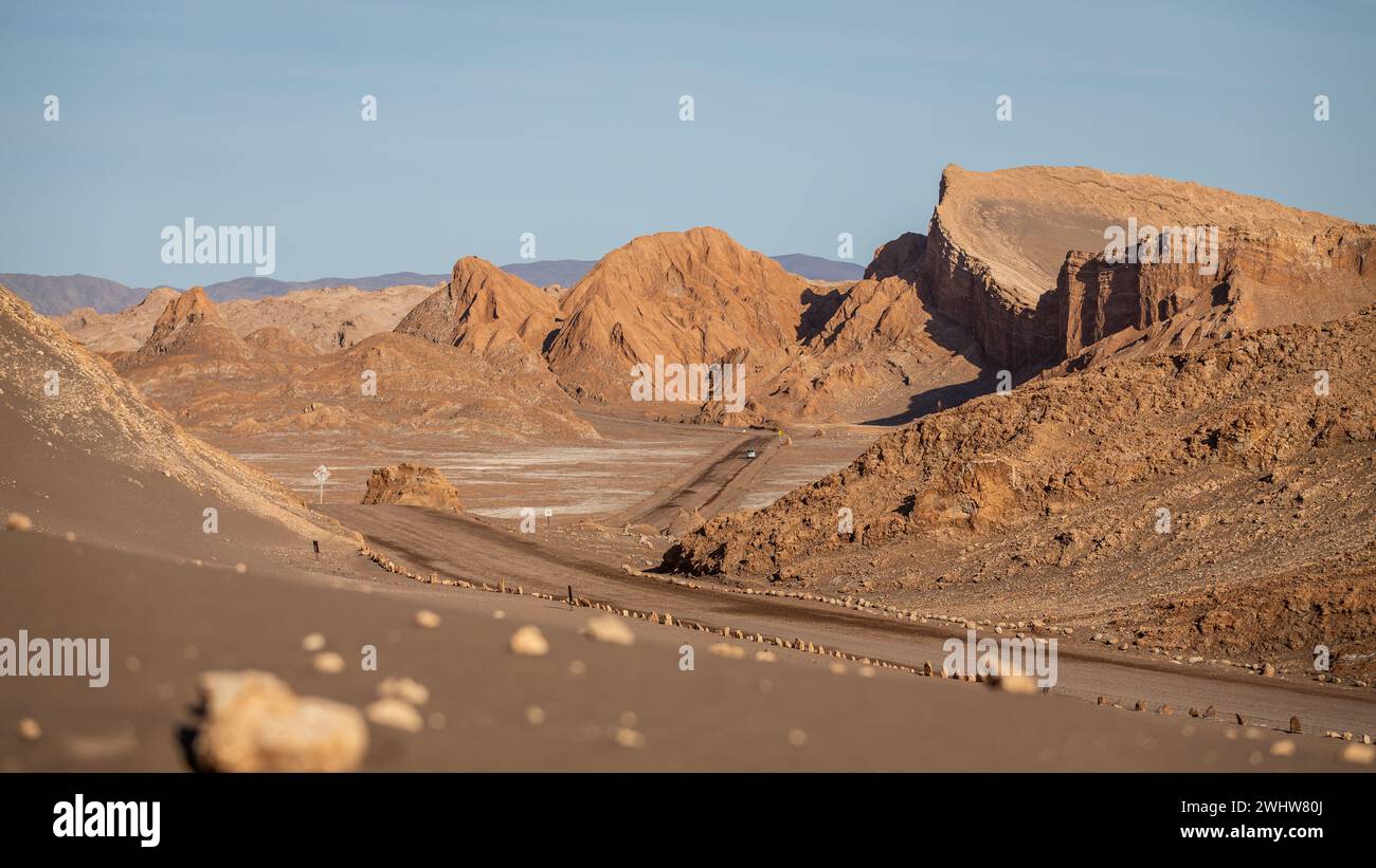 A road leads through towering, bright red rock formations in the middle of the Valley of the Moon, Valle de la Luna. Stock Photo