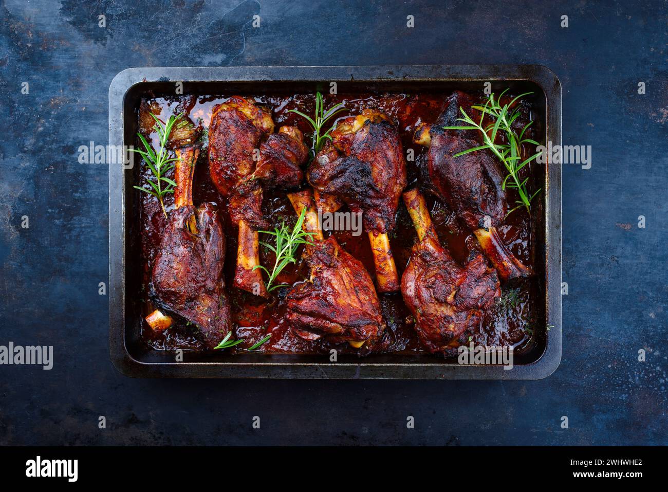 Traditional braised slow cooked lamb knuckle in red wine sauce with herbs served as top view in