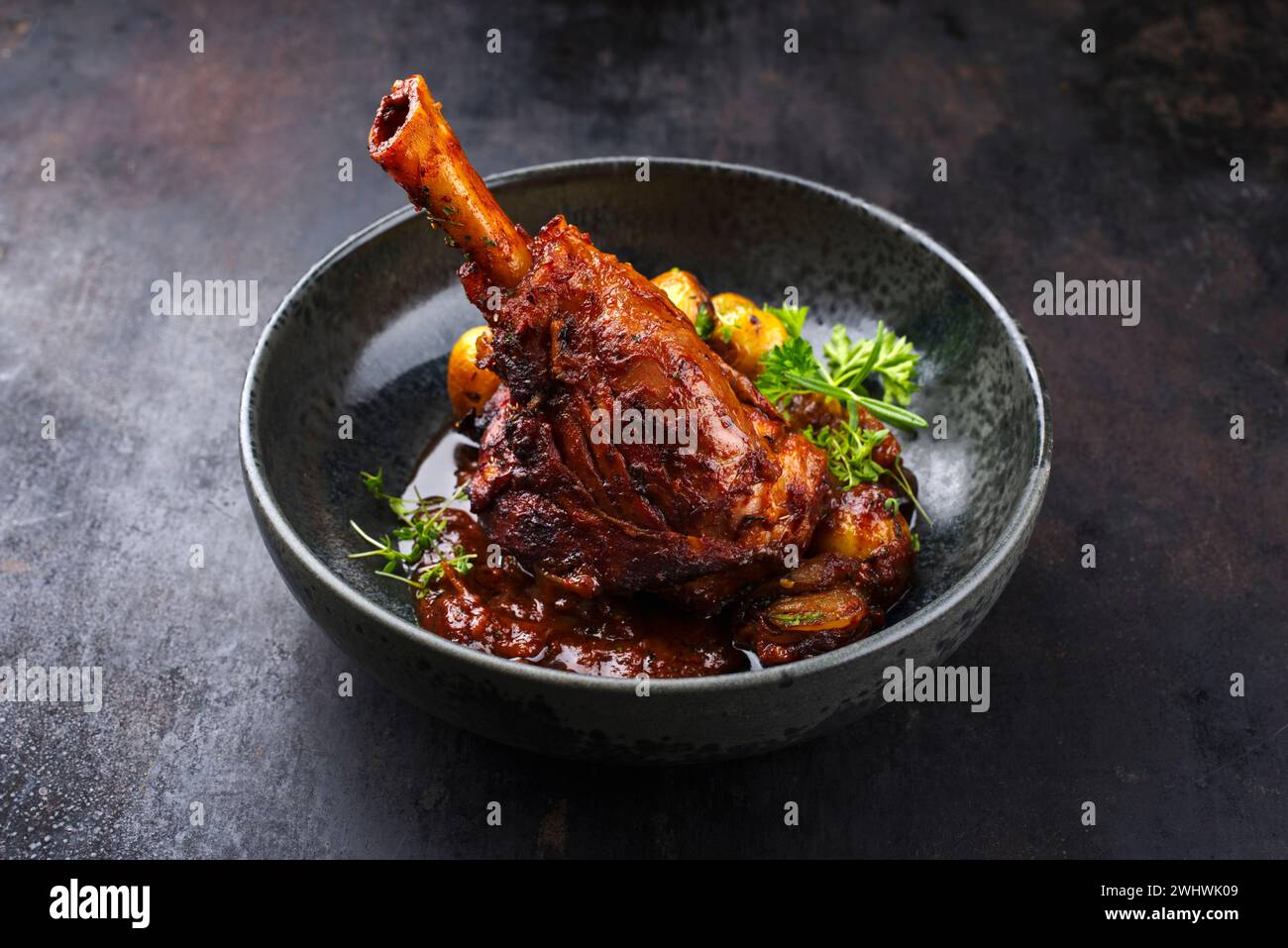 Traditional braised slow cooked lamb knuckle in red wine sauce with mini roast potatoes and