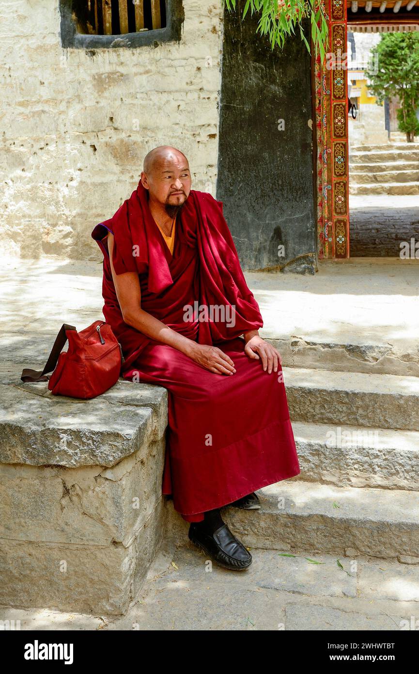 An elderly Buddhist monk rests on the stone steps at Sera Monastery in Lhasa. Stock Photo
