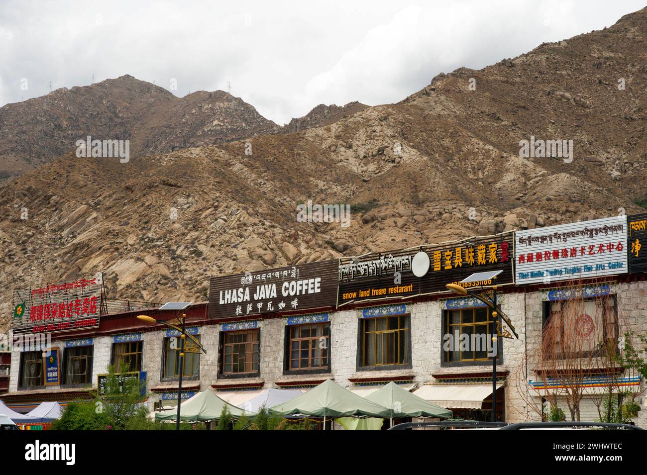 Signs written in Chinese carachters, Tibetan script and English mark a shops in a strip mall in Lhasa area of Tibet Autonomous Region of China. Stock Photo