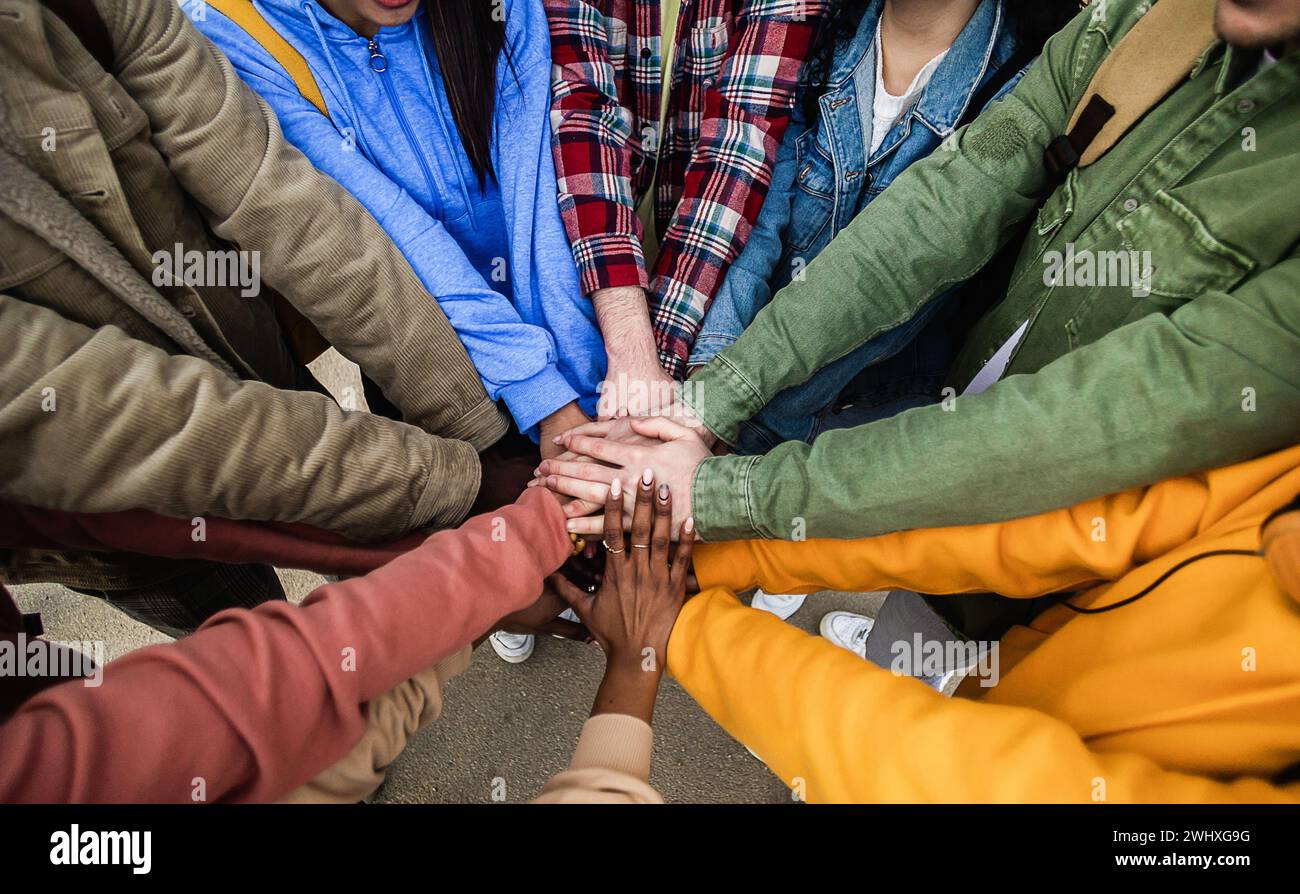 Diverse group of young friends stacking hands outdoors showing support ...