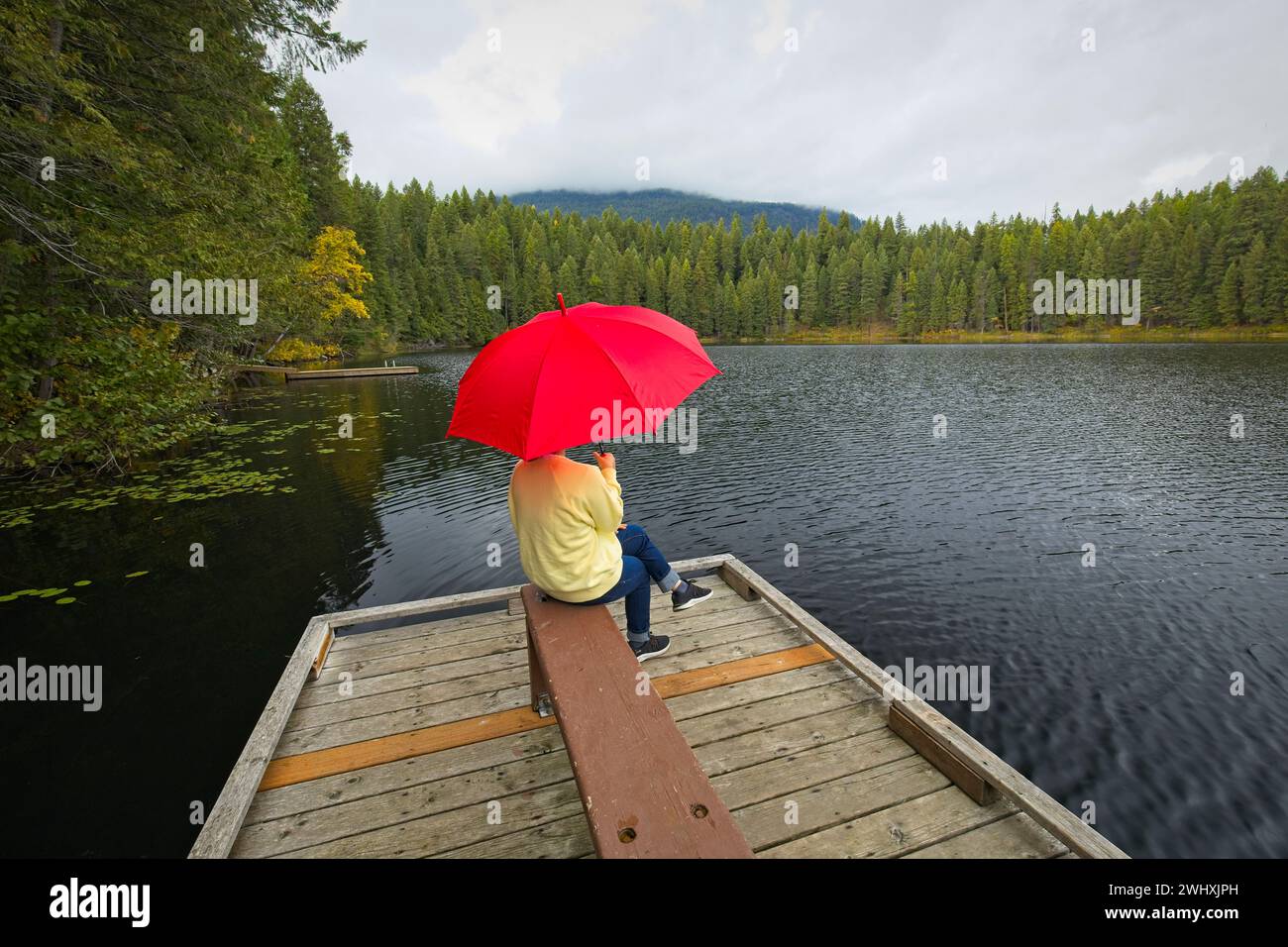 Woman holding umbrella enjoys the lake. Stock Photo