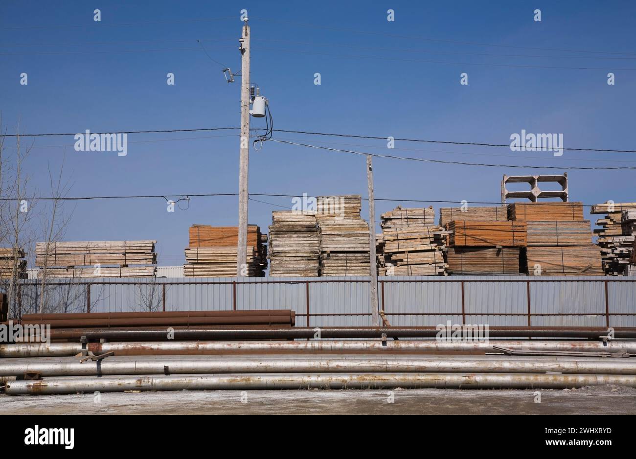 Steel pipes and stacked lumber in industrial storage yard, Quebec