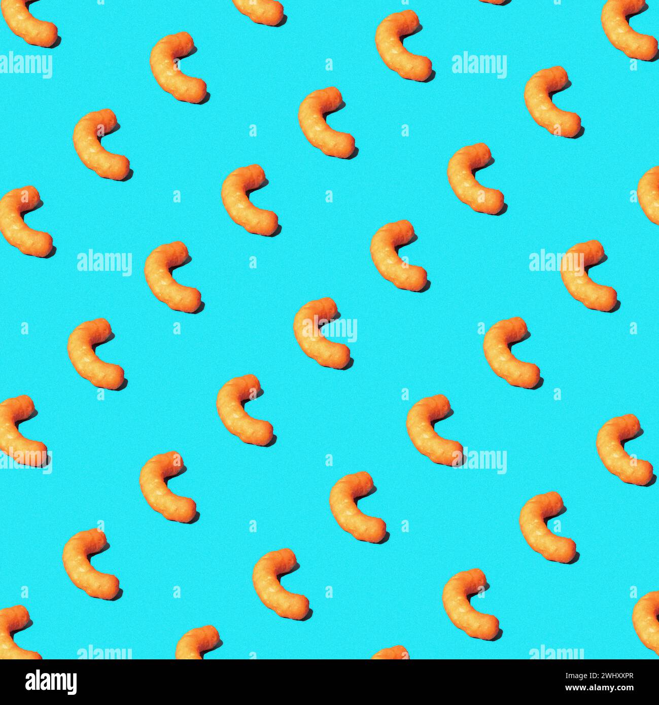 Cheese puffs in a repeating pattern on a brightly lit studio blue