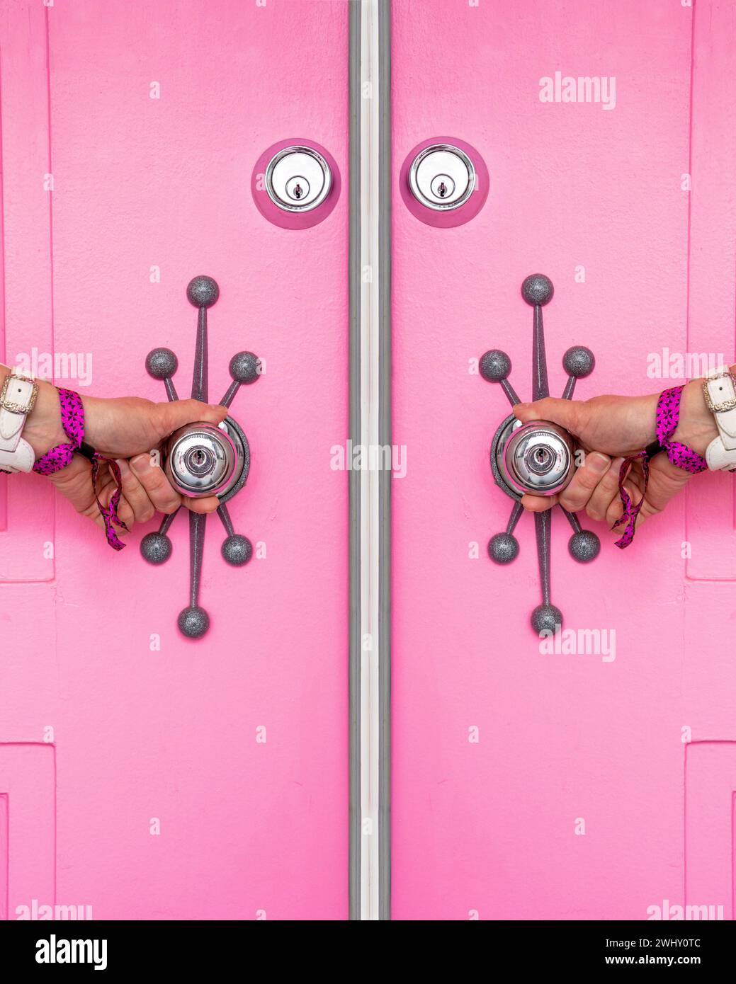 Pink door with a woman's hands holding the doorknobs in Palm Springs, California Stock Photo