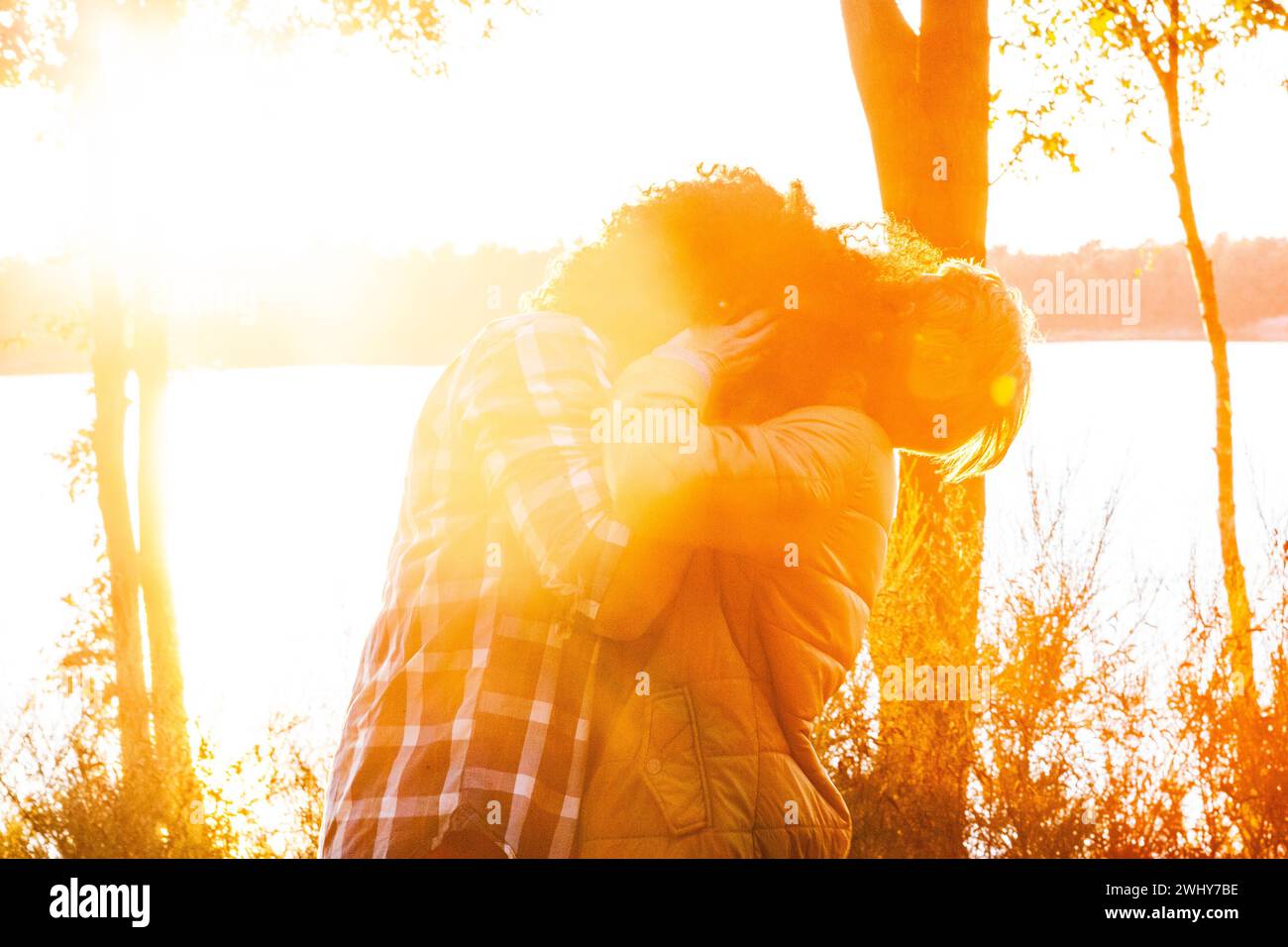 Interracial Couple Sharing Sunset Kiss Stock Photo