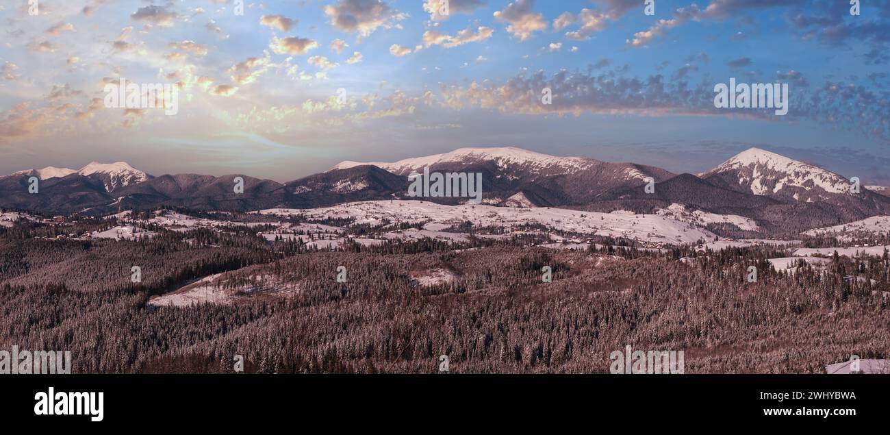 Winter remote alpine village outskirts, countryside hills, groves and farmlands view from mountain slope Stock Photo