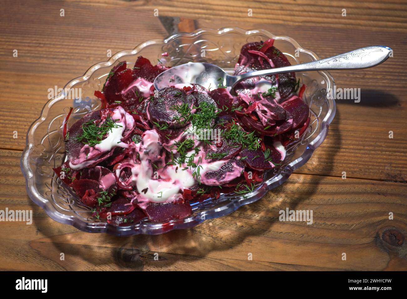 Beetroot salad with dill and a creamy dressing, healthy vegetarian dish in a glass bowl on a rustic wooden table, selected focus Stock Photo