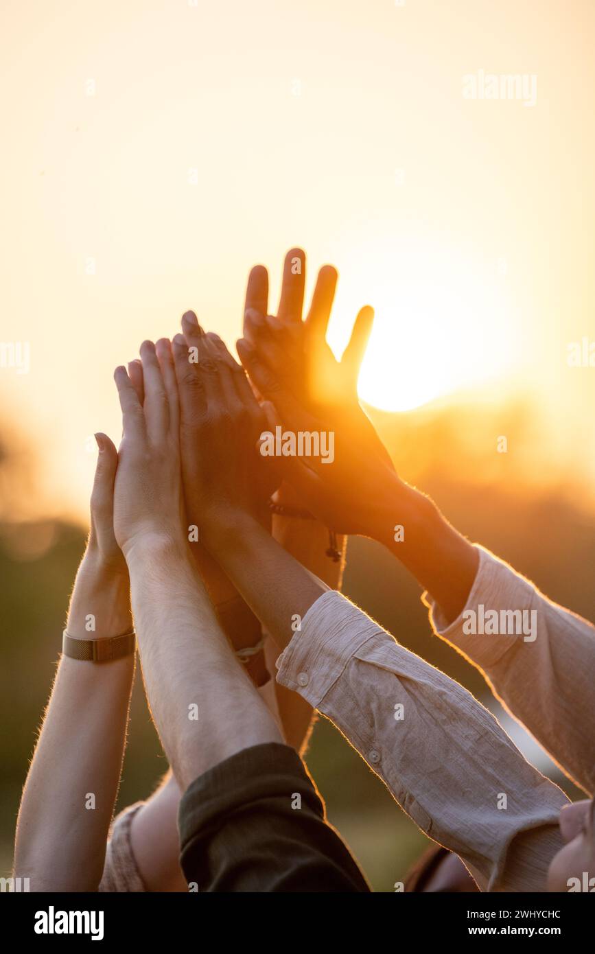 Diverse Group High-Fiving at Sunset Stock Photo