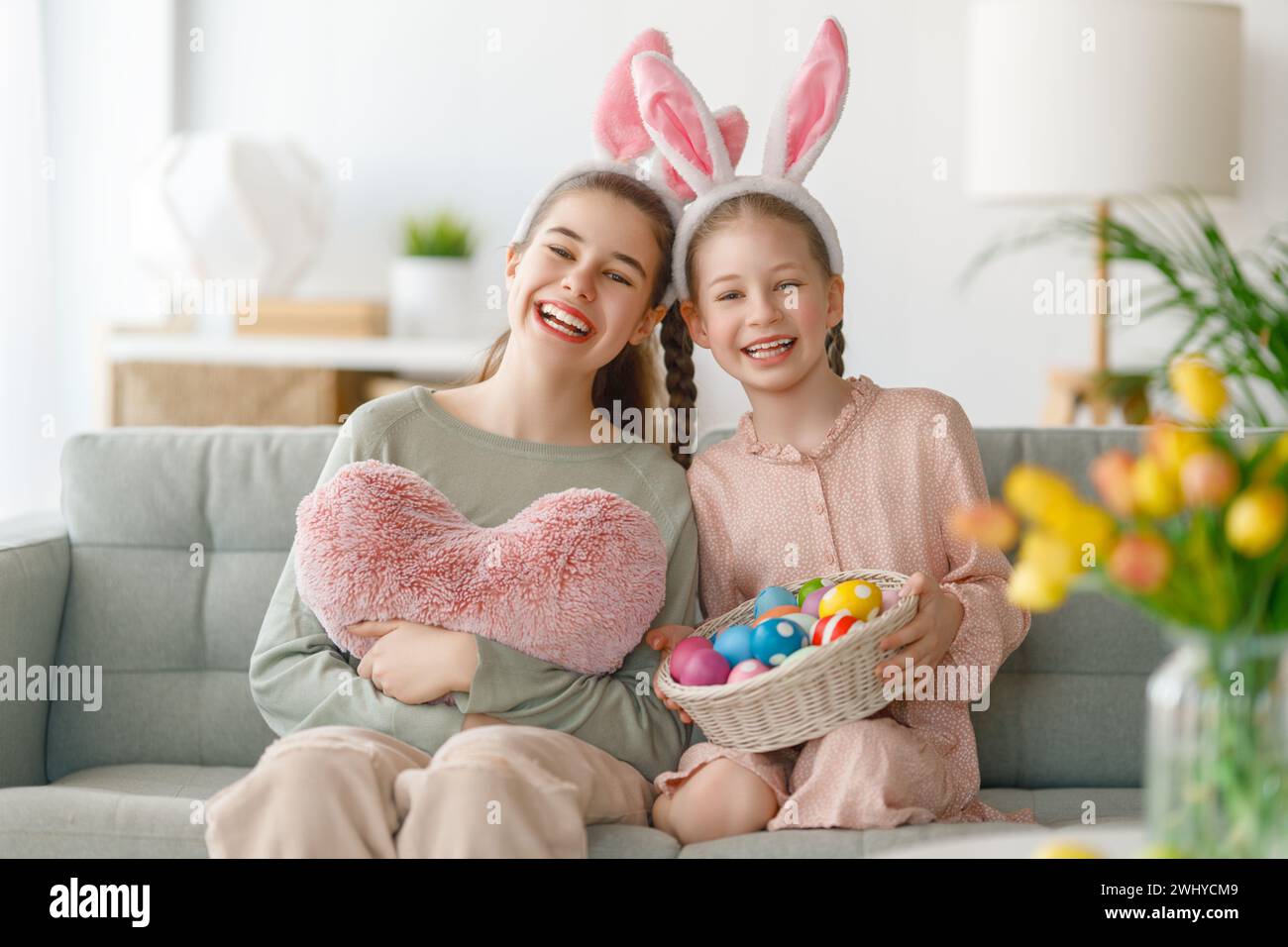 Cute little children wearing bunny ears on Easter day. Girls with painted eggs. Stock Photo