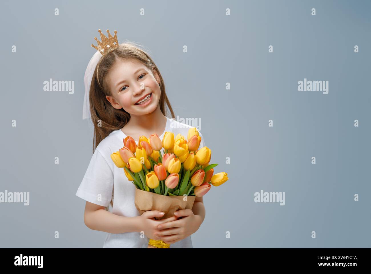 Beautiful girl with pink flowers in hands on grey wall background. Stock Photo