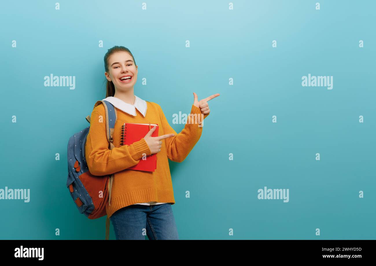 Back to school and happy time. Cute industrious teenager on color paper wall background. Girl with backpack. Teen ready to study. Stock Photo