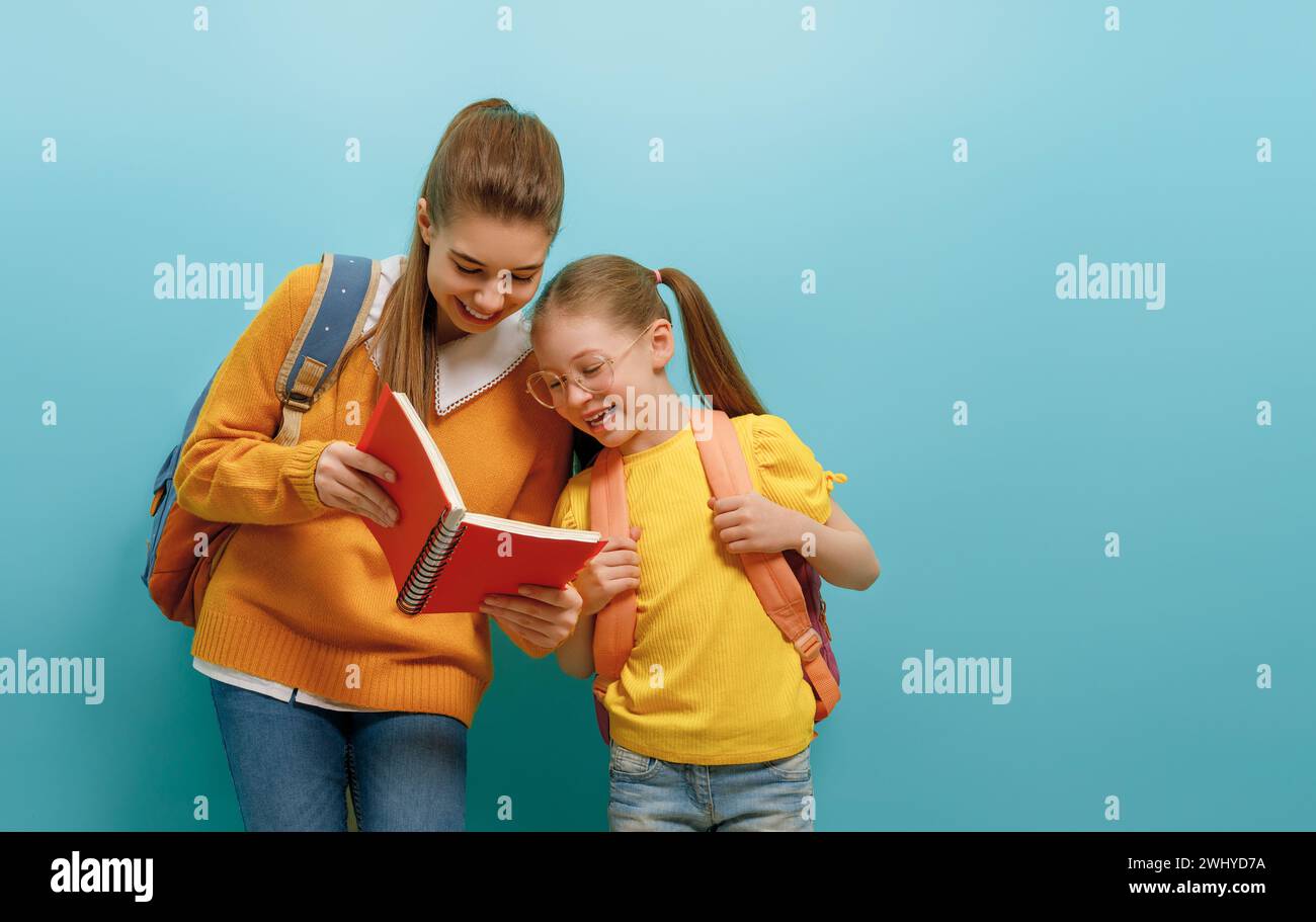 Two schoolers children standing on light blue background. Happy time back to school. Stock Photo