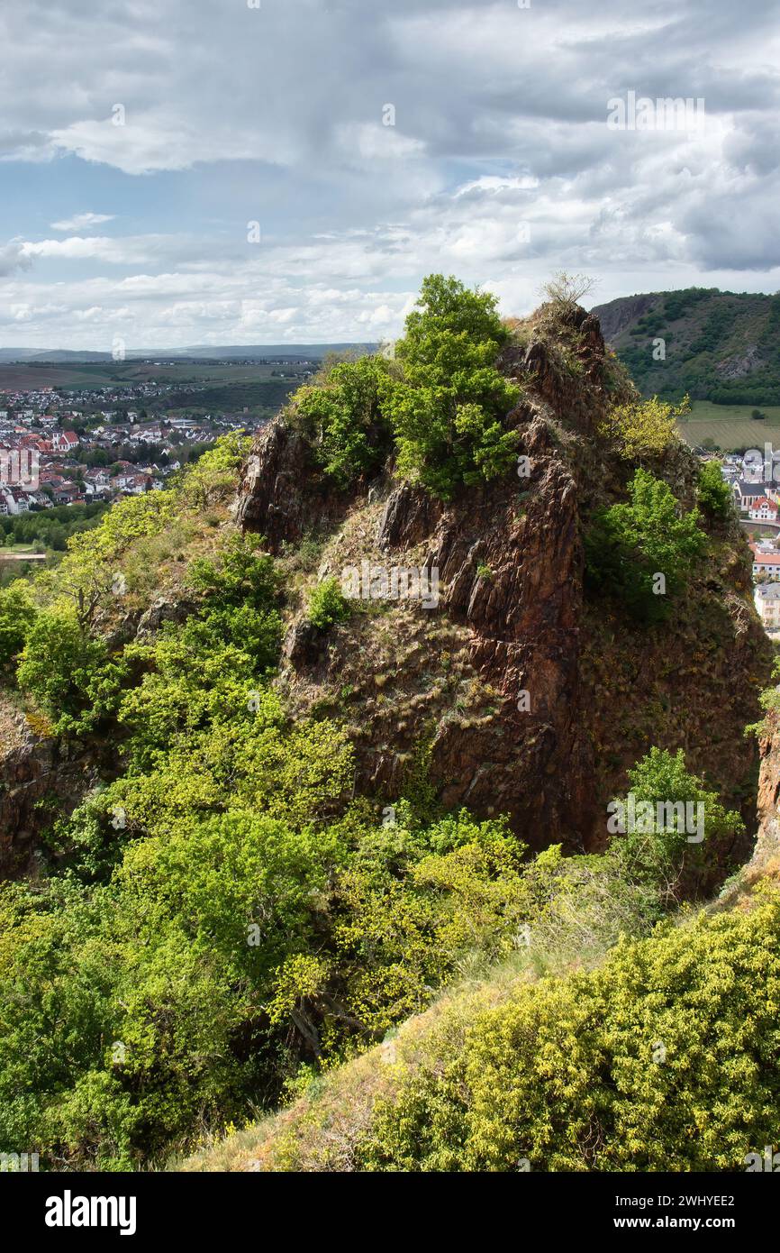 Sun shining on a rock with green plants at the top of Rotenfels overlooking Bad Munster, Germany on a spring day. Stock Photo
