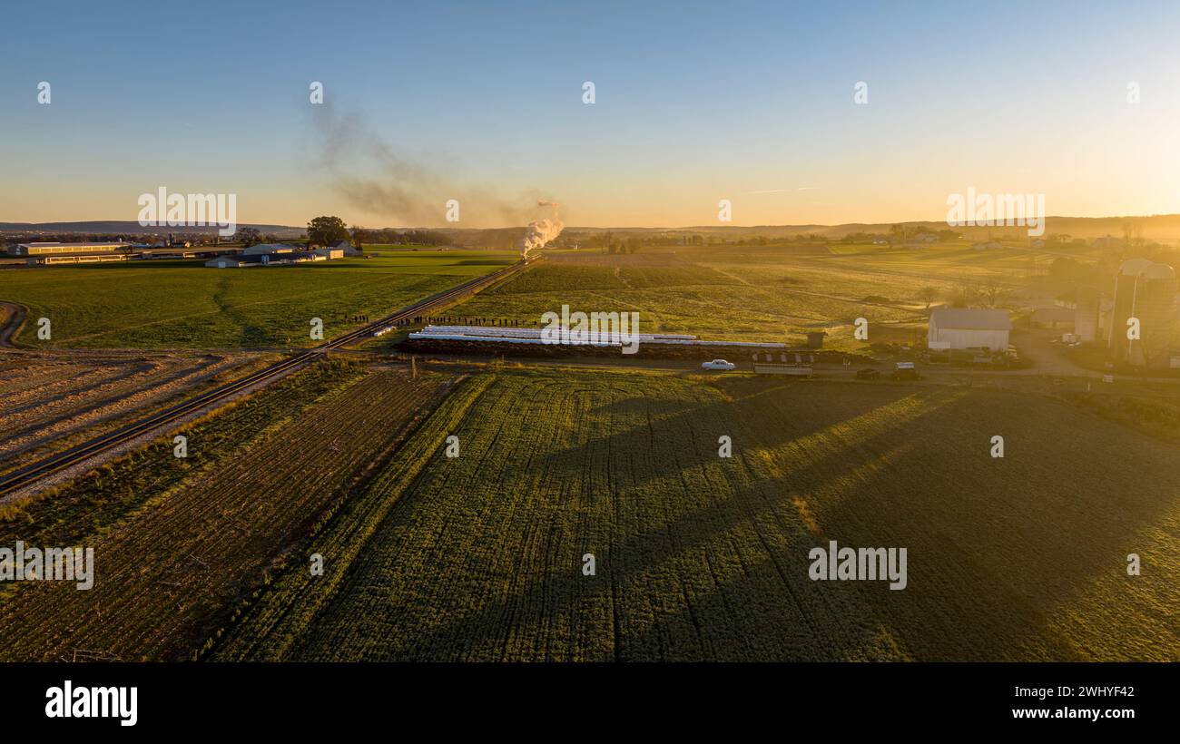 Aerial View at Sunrise of a Steam Passenger Train Approaching Blowing A Lot of Smoke Stock Photo