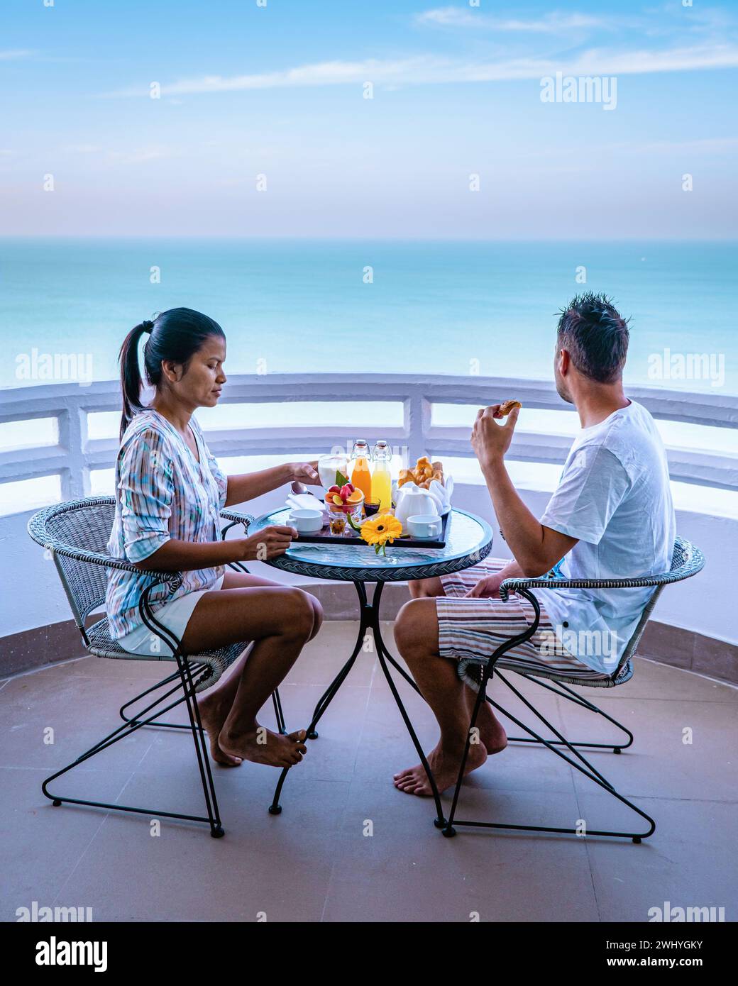 Couple having breakfast on balcony looking out over the ocean on vacation in Thailand Stock Photo