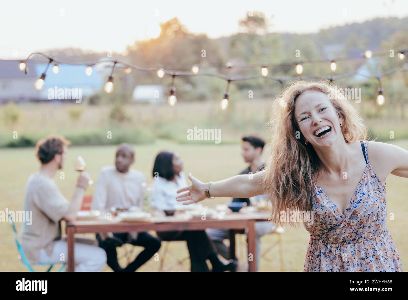 Joyful Blonde Enchants Sunny Garden BBQ with Laughter Stock Photo