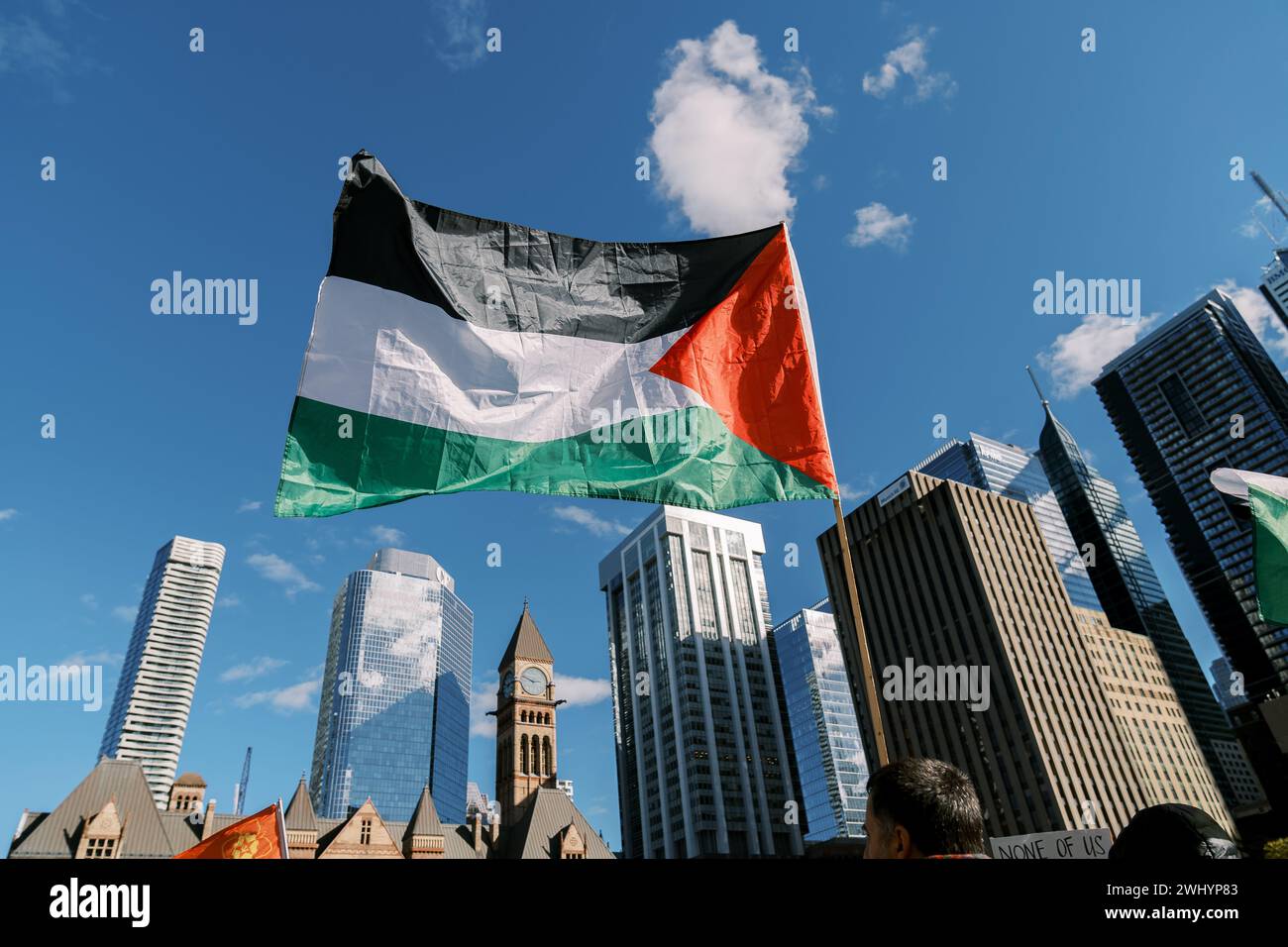 Toronto, Canada - 28 October 2023: Palestinian flag flies high amidst the city skyline, with skyscrapers and an old clock tower Stock Photo