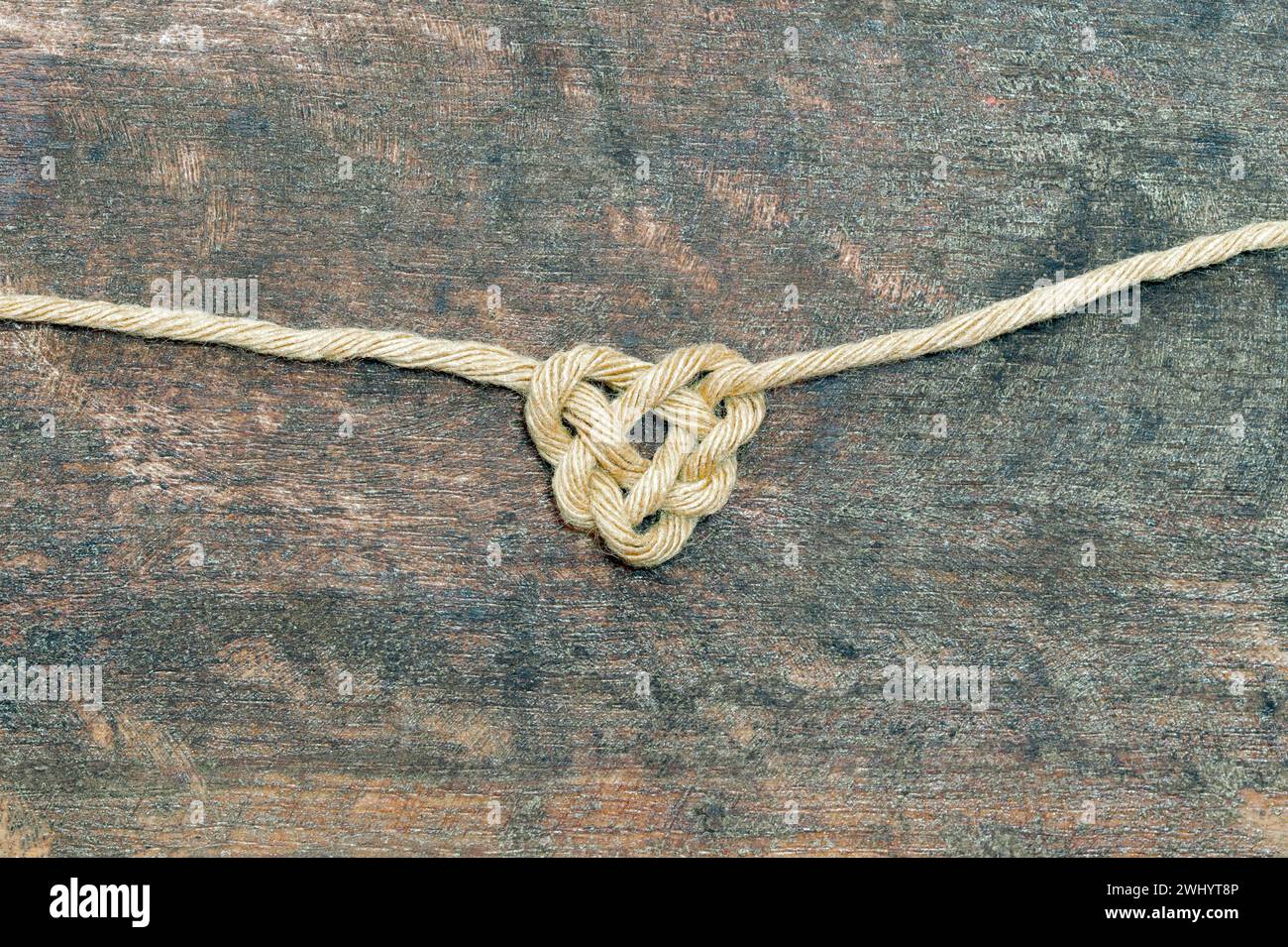 Sisal rope bonding on wooden Background, in heart shape knot on metal background. Love symbol. Love, Stock Photo