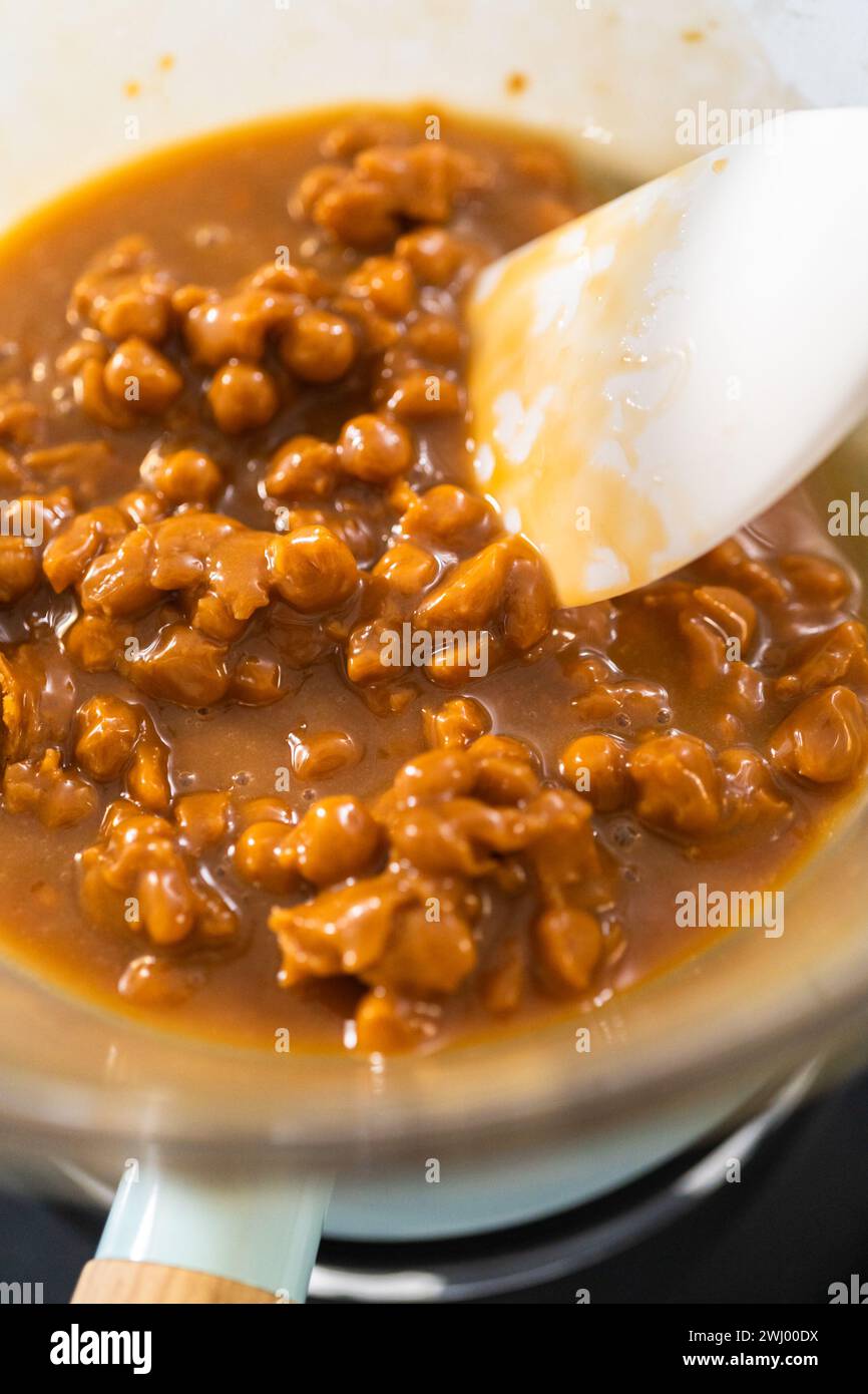 Melting chocolate chips and other ingredients in a glass mixing bowl over boiling water to