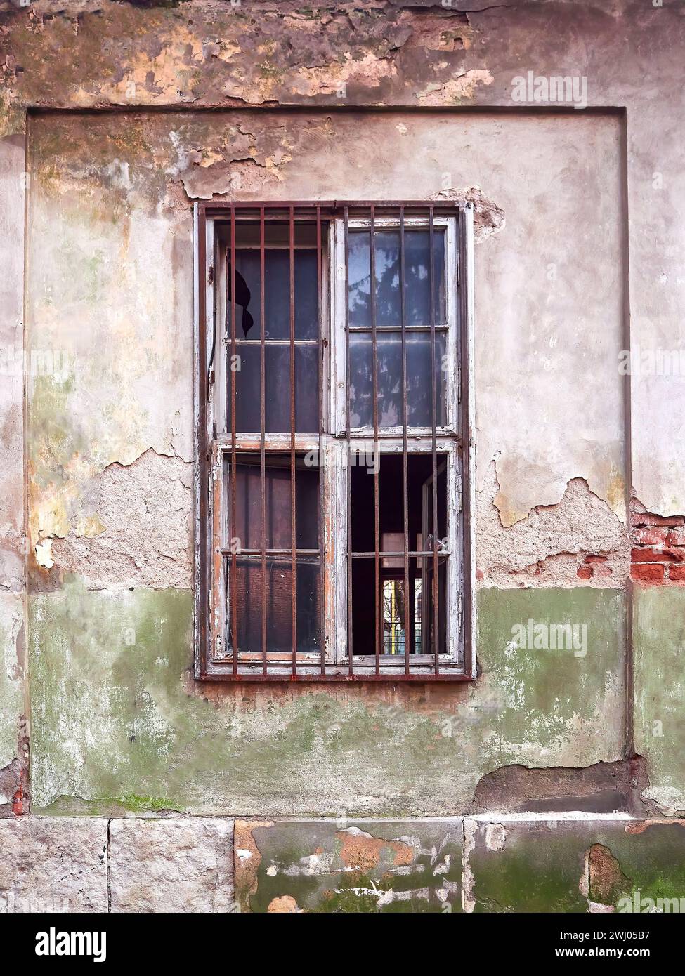 Old narrow window with a metal decorative grille on building. Old plastered wall with window Stock Photo