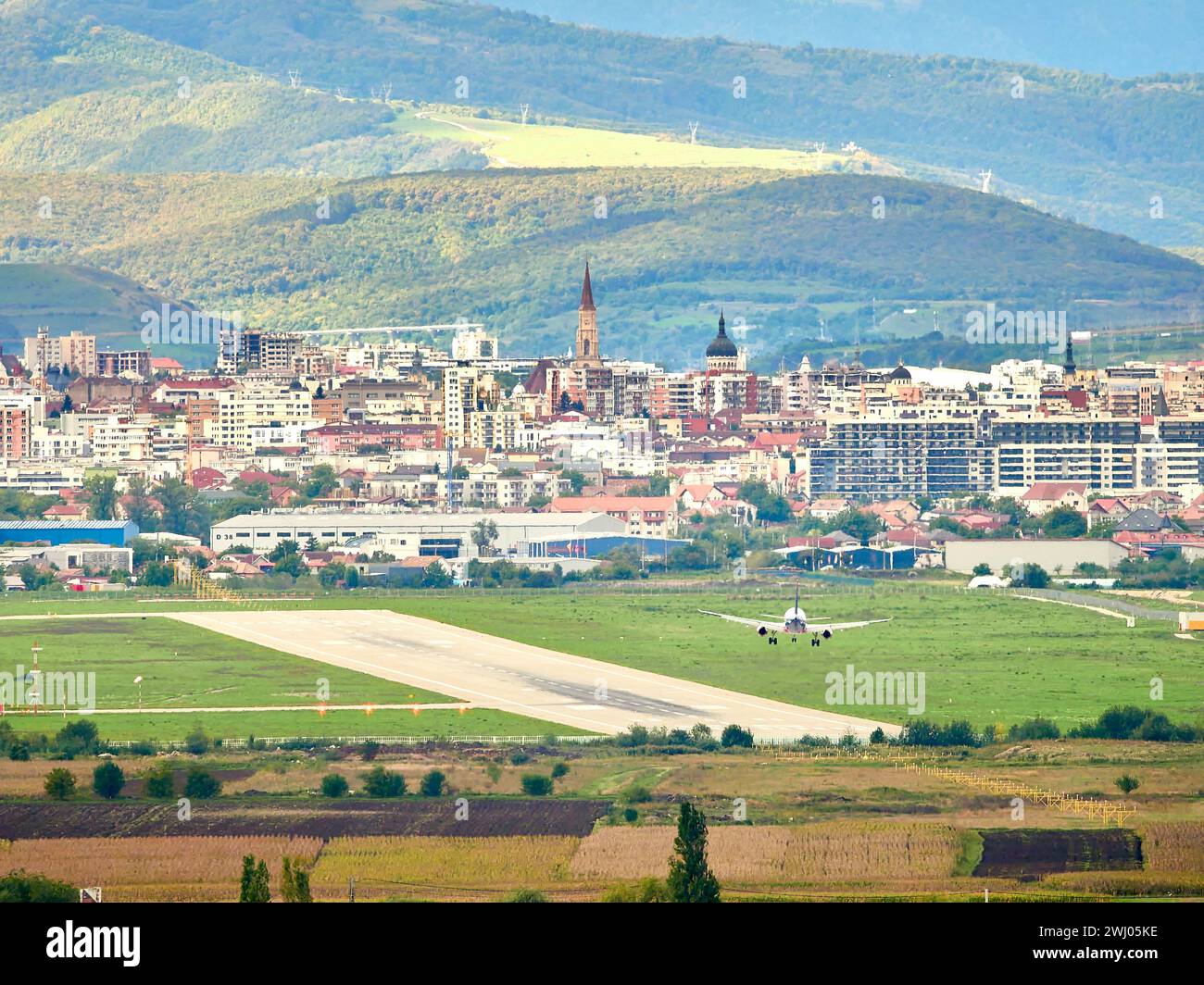 Avram Iancu airport runway in Cluj with plane landing. East side view of Cluj Napoca. Dramatic sunlight, different view over the city. Stock Photo