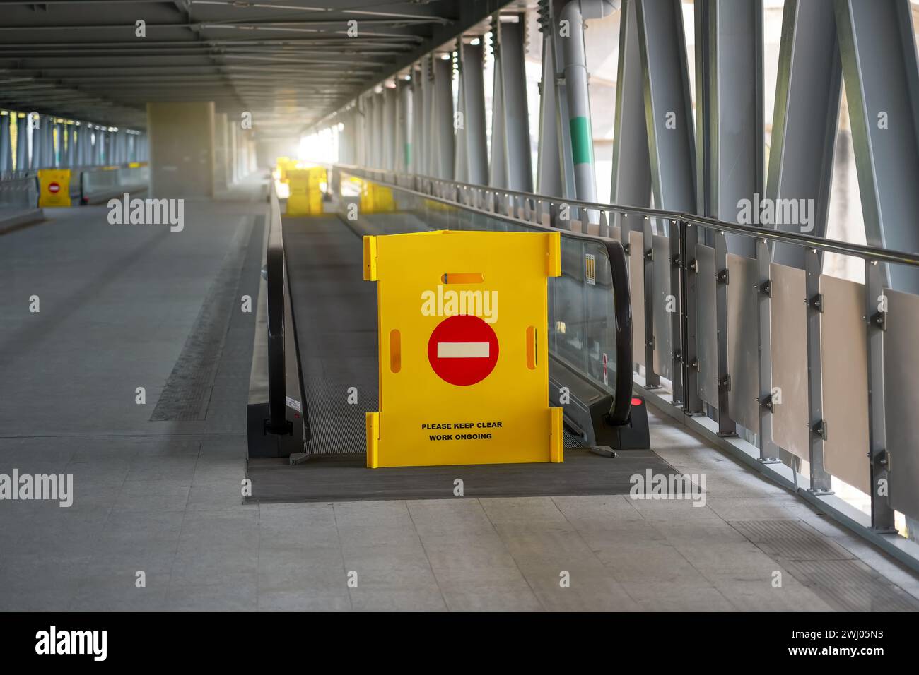 Yellow fence with a brick sign, passage is prohibited on a travelator, an elevated pedestrian crossing at the airport, railway station Stock Photo