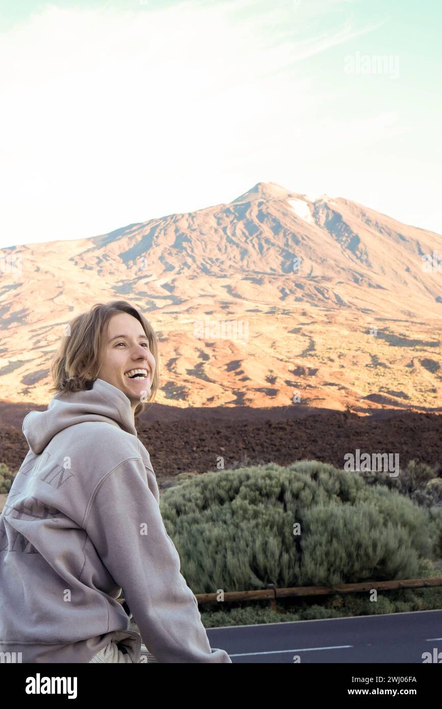 A joyful young man is pictured enjoying the breathtaking backdrop of Teide Mountain bathed in the warm glow of a sunset. Stock Photo
